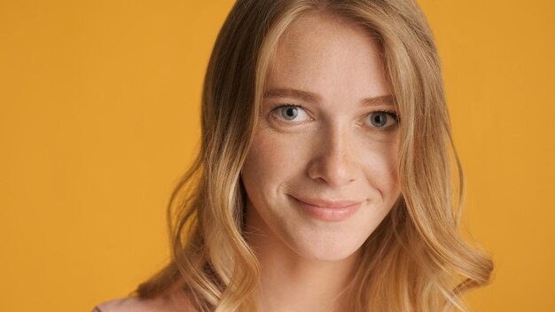 Close up beautiful blond girl dreamily looking in camera over colorful background Cute face