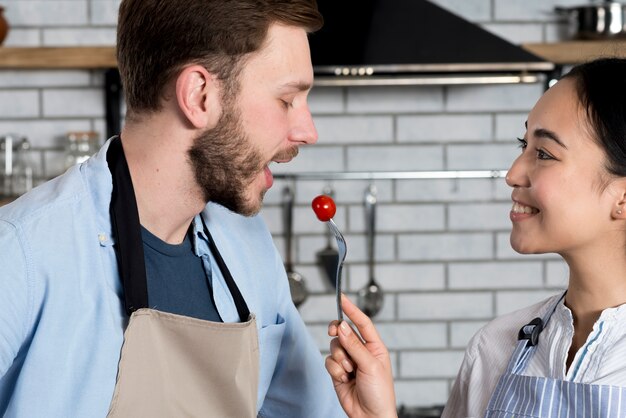 Foto gratuita primo piano di bella coppia che alimenta pomodoro in cucina