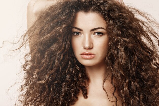 Close up of beautiful girl with curly hair  over pink wall