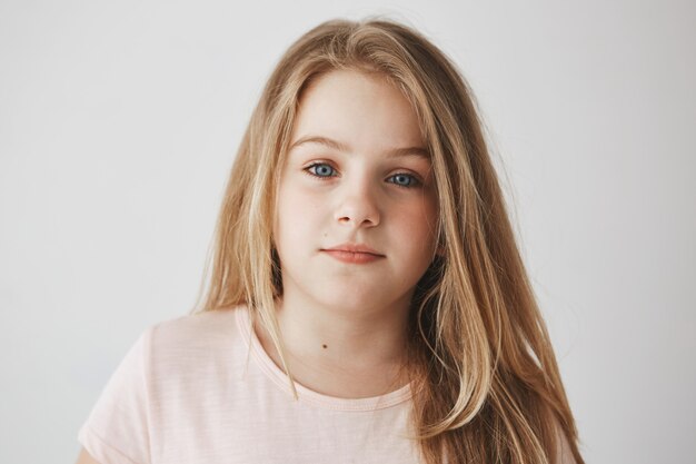 Close up of beautiful little blonde girl with light long hair and bright blue eyes. Child  with relaxed expression