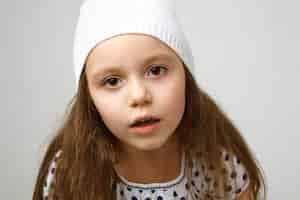 Free photo close up of beautiful little girl preschooler with big brown eyes and loose hair posing against white