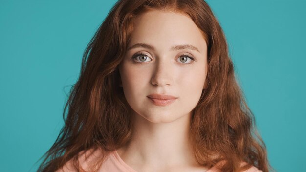 Close up beautiful redhead girl intently looking in camera over colorful background