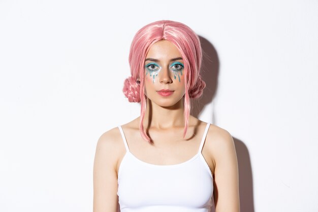 Close-up of beautiful woman celebrating halloween in costume of fairy, with pink wig and bright makeup, standing.