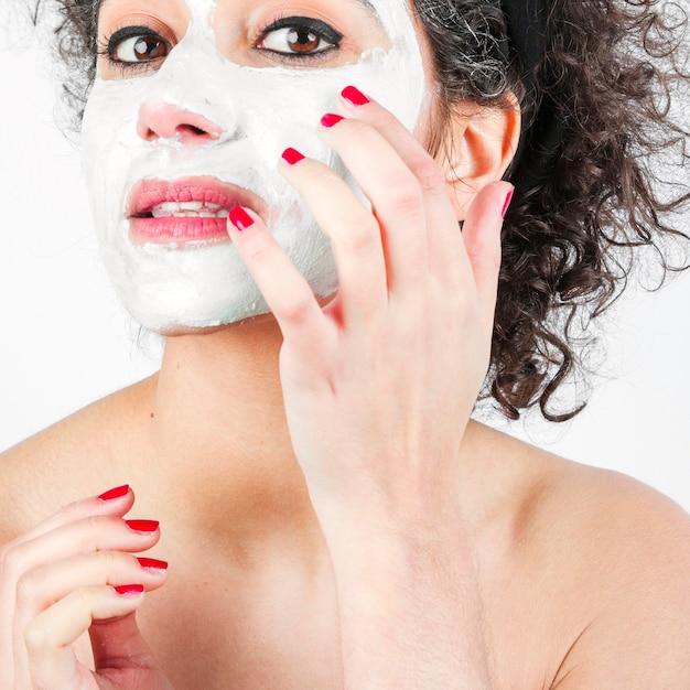 Free photo close-up of beautiful young woman applying white face mask