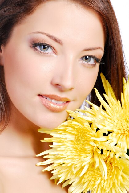 Close-up beautiful young woman face with the yellow camomile