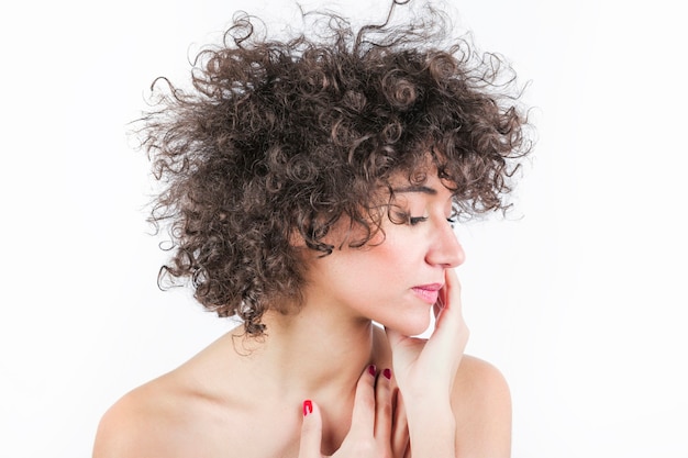 Close-up of a beautiful young woman touching skin over white background