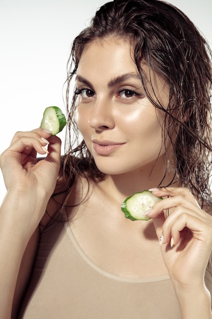 Close up of beautiful young woman over white wall. shiny and healthy skin