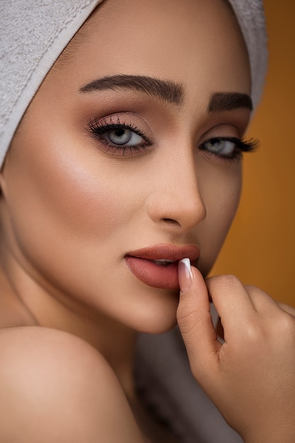 Close-up of beautiful young woman with bath towel on head covering her breasts