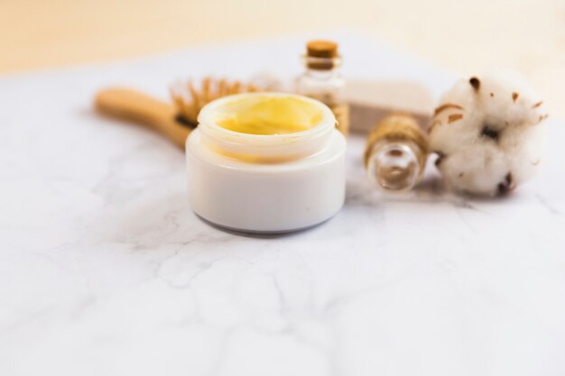 Close-up of beauty cream bottle and cotton flower plant