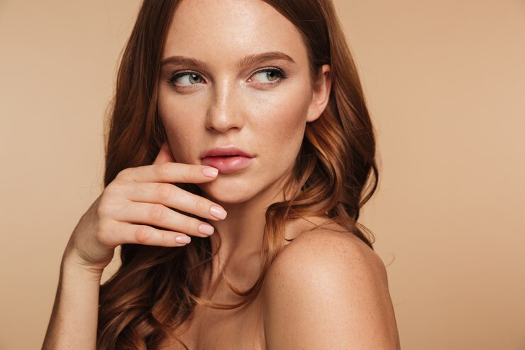 Free Photo close up beauty portrait of mystery ginger woman with long hair posing sideways while looking away