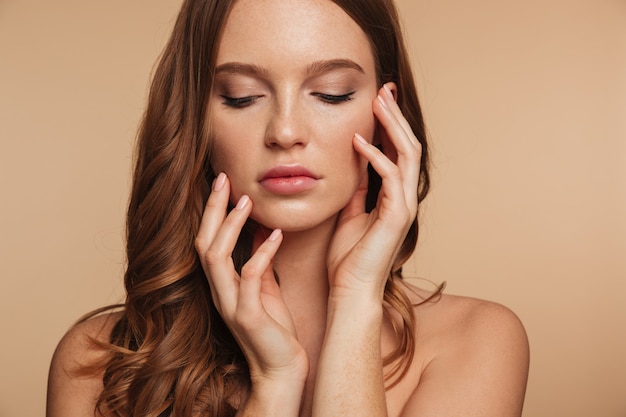 Foto gratuita chiuda sul ritratto di bellezza della donna sensuale dello zenzero con capelli lunghi che posano con le armi vicino al viso