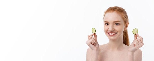 Free photo close up beauty portrait of a smiling beautiful half naked woman holding cucumber slices at her face