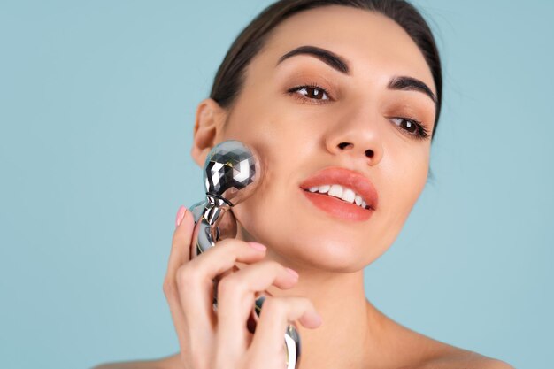 Close up beauty portrait of a woman with perfect skin and natural make-up, plump nude lips, holding a roller massager for face and neck