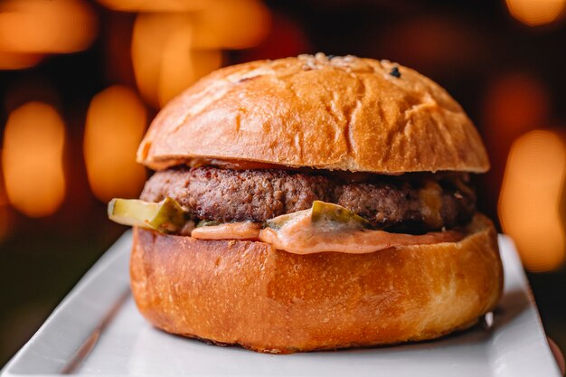 Close up of beef burger with sauce pickled cucumber served at restaurant