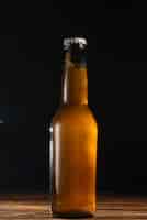 Free photo close-up of a beer bottle on wooden desk