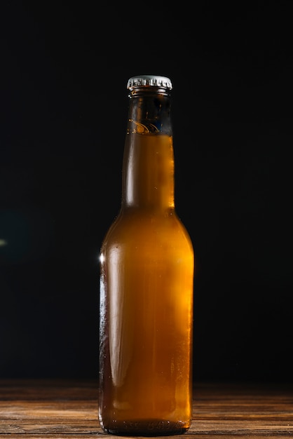 Close-up of a beer bottle on wooden desk