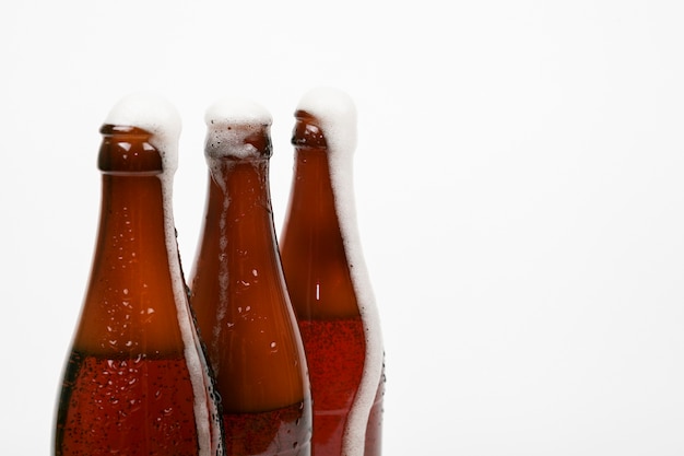 Close up beer bottles with foam and copy space