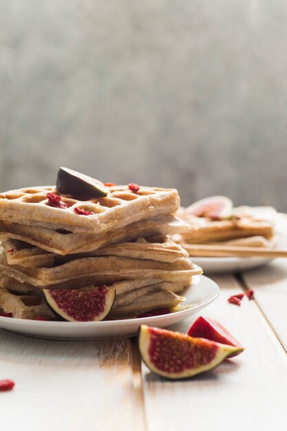 Close-up of belgian waffles and fig fruit served in white plate