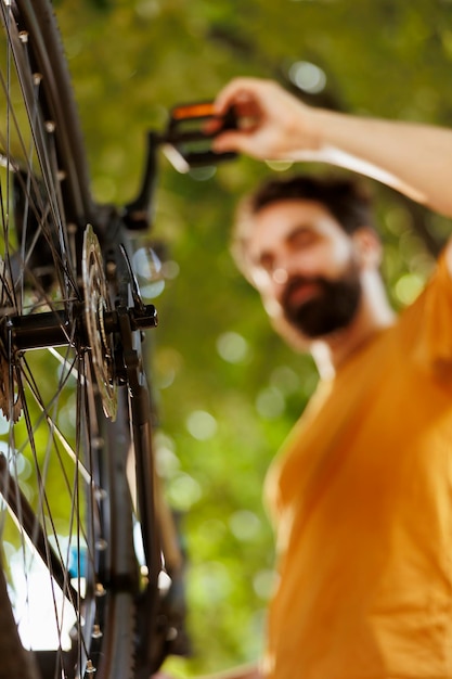 Close-up of bicycle rear derailleur and cogset being serviced and adjusted outside for leisure cycling. detailed image of bike components being maintained and tested outdoor by sports-loving caucasian