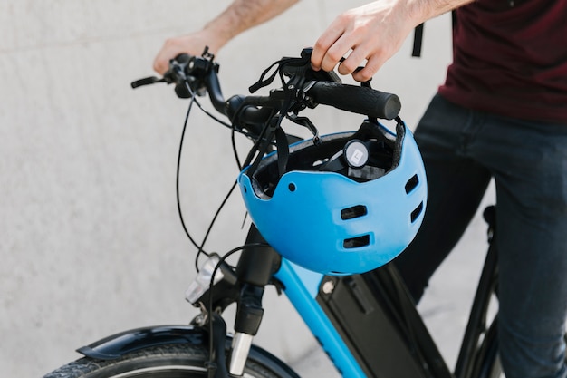 Free photo close up bicyclist putting helmet on bycicle handle