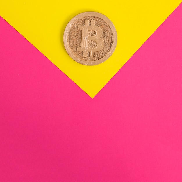 黄色とピンクの背景にビットコインのクローズアップ