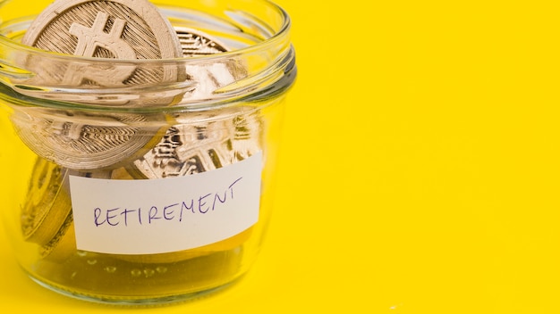 Close-up of bitcoins in the retirement glass jar on yellow background