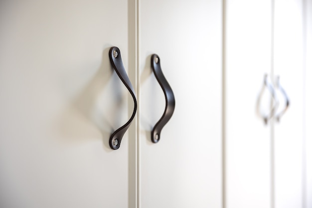 Close-up of black knobs on a white cabinet.