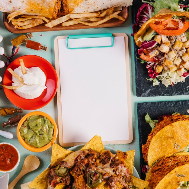Close-up blank clipboard and Mexican dishes