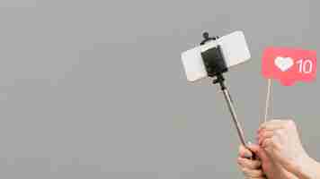 Free photo close-up blogger holding selfie stick with mobile phone