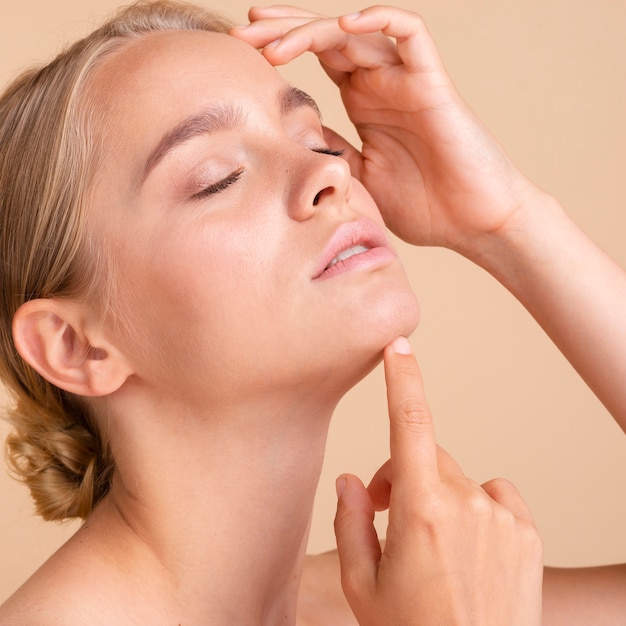 Close-up blonde model posing with peach background