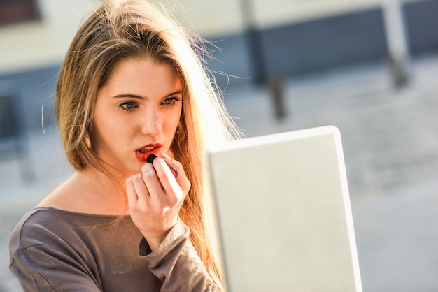 Free photo close-up of blonde woman painting her lips with a lipstick