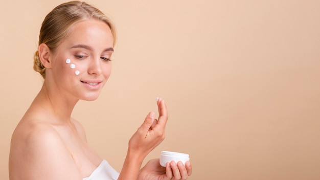 Close-up blonde woman with cream on her face