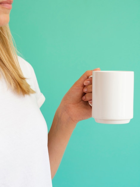 Donna bionda del primo piano con la tazza bianca