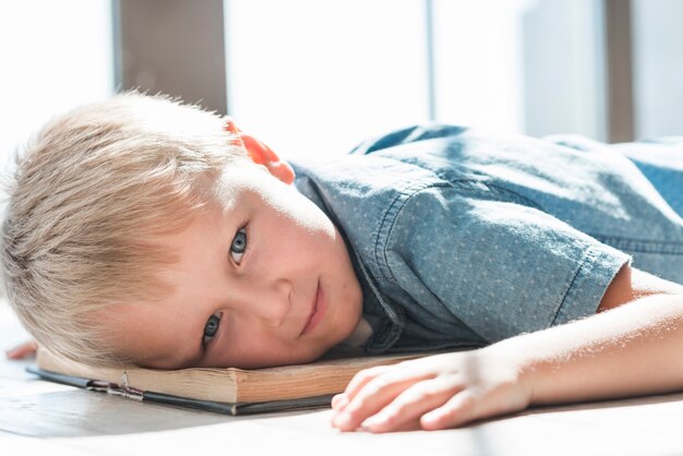 Close-up of blonde young boy leaning head on an open book