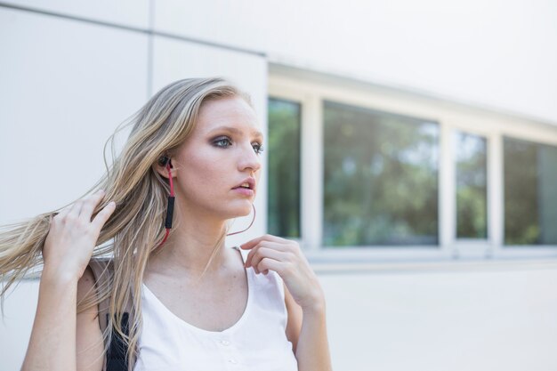 Close-up of blonde young woman listening music on earphone