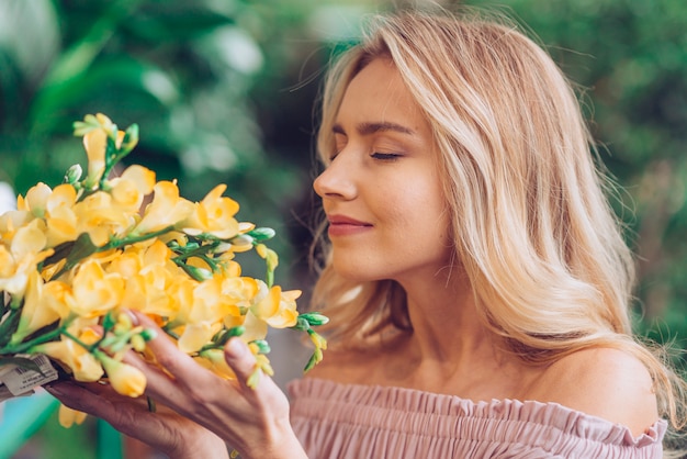 Close-up of a blonde young woman smelling the freesia flowers