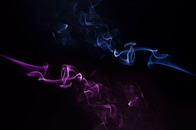 Close-up of blue and purple smoke swirling against black backdrop