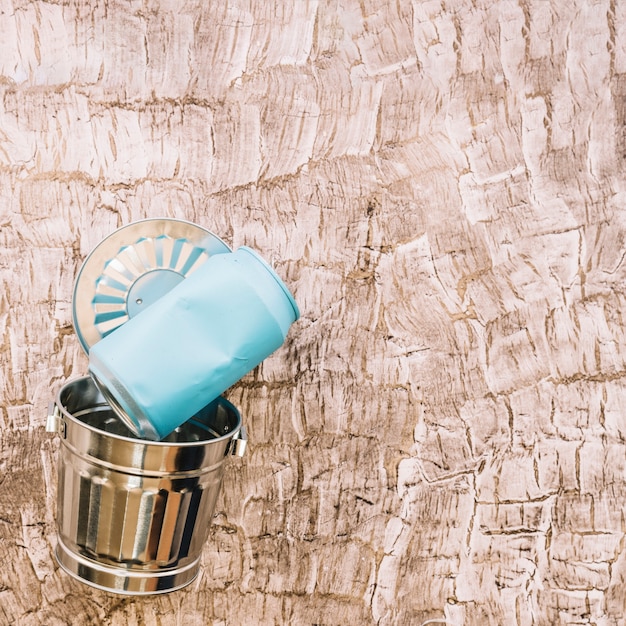 Close-up of blue tin can over metal dustbin