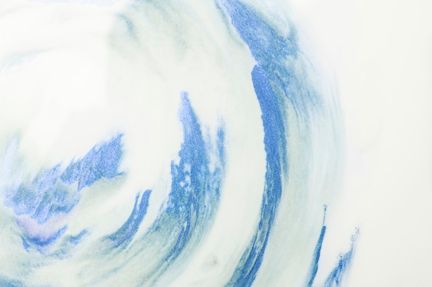 白い泡の背景の上の青い水彩画ストロークのクローズアップ