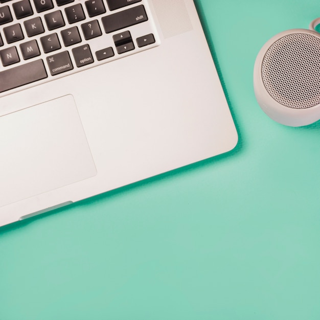 Close-up of bluetooth speaker and laptop on green background