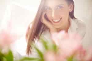 Free photo close-up blurred flowers with happy woman background