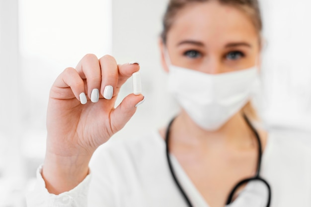 Free photo close-up blurry doctor holding pill