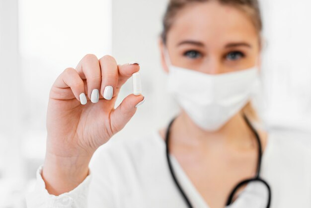 Close-up blurry doctor holding pill