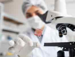 Free photo close up blurry scientist holding glass slide