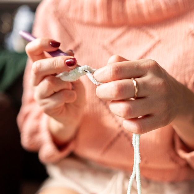 Close-up blurry woman crocheting indoors