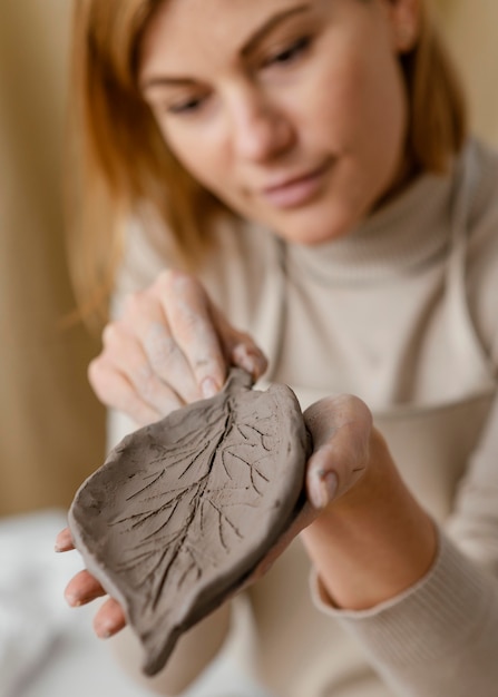 Free photo close-up blurry woman holding clay leaf