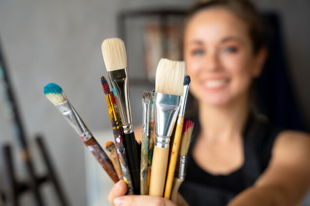 Close up blurry woman holding different brushes
