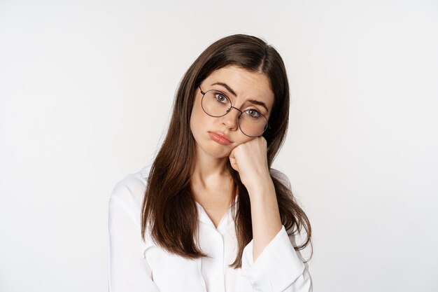 Close up of bored brunette girl looking unamused, sad, watching smth boring, standing over white background. Copy space