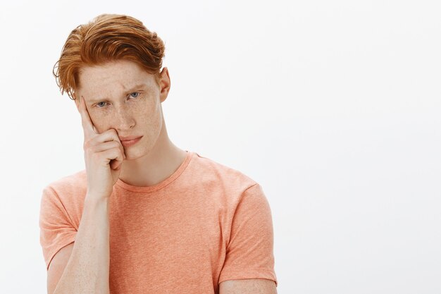 Close-up of bored and unamused redhead college man looking at camera indifferent