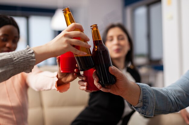 close up of bottles and cups of beer from cheerful friends after work at office